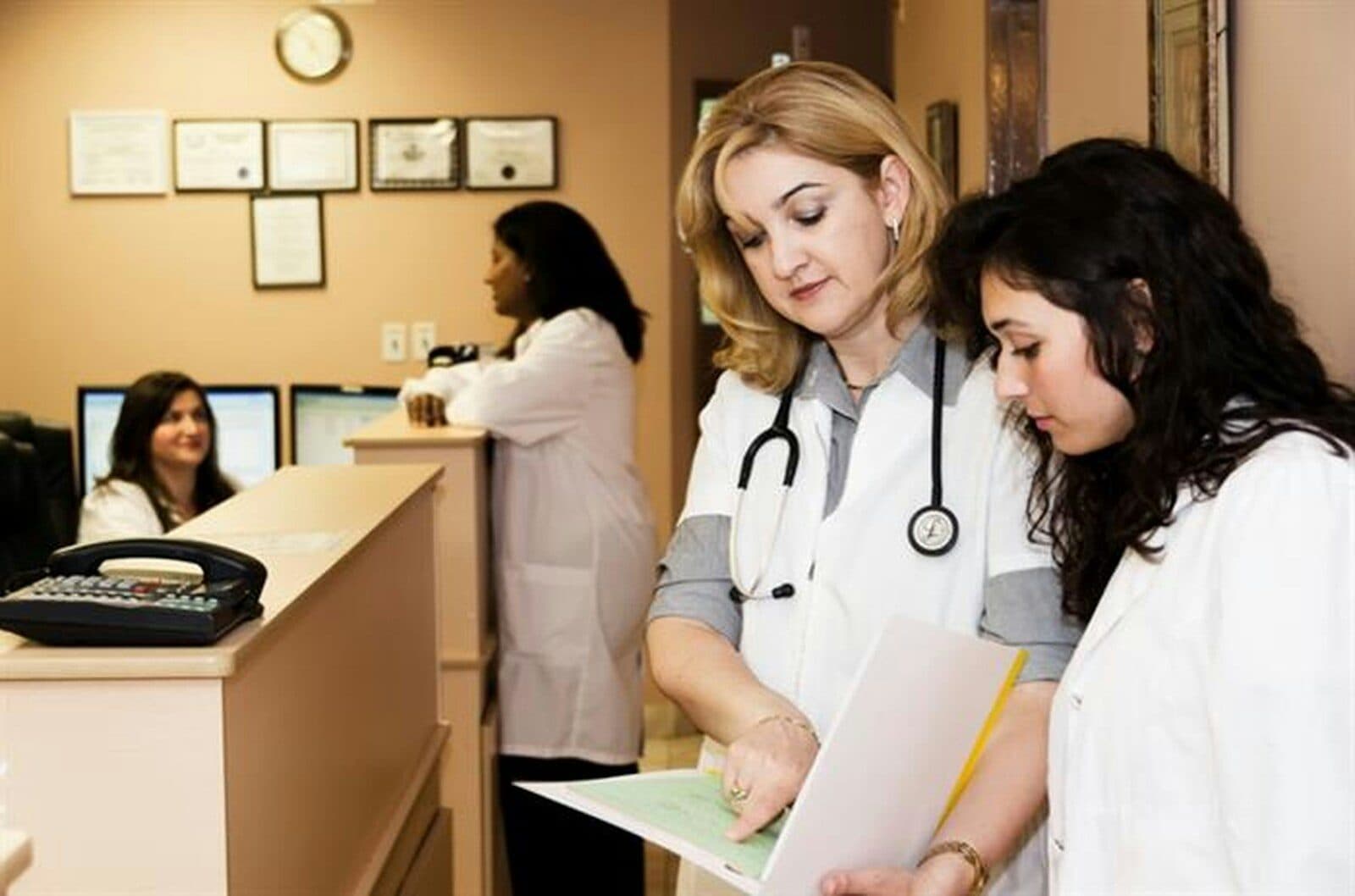 Front desk staff at a medical practice going over paperwork beside the reception phone