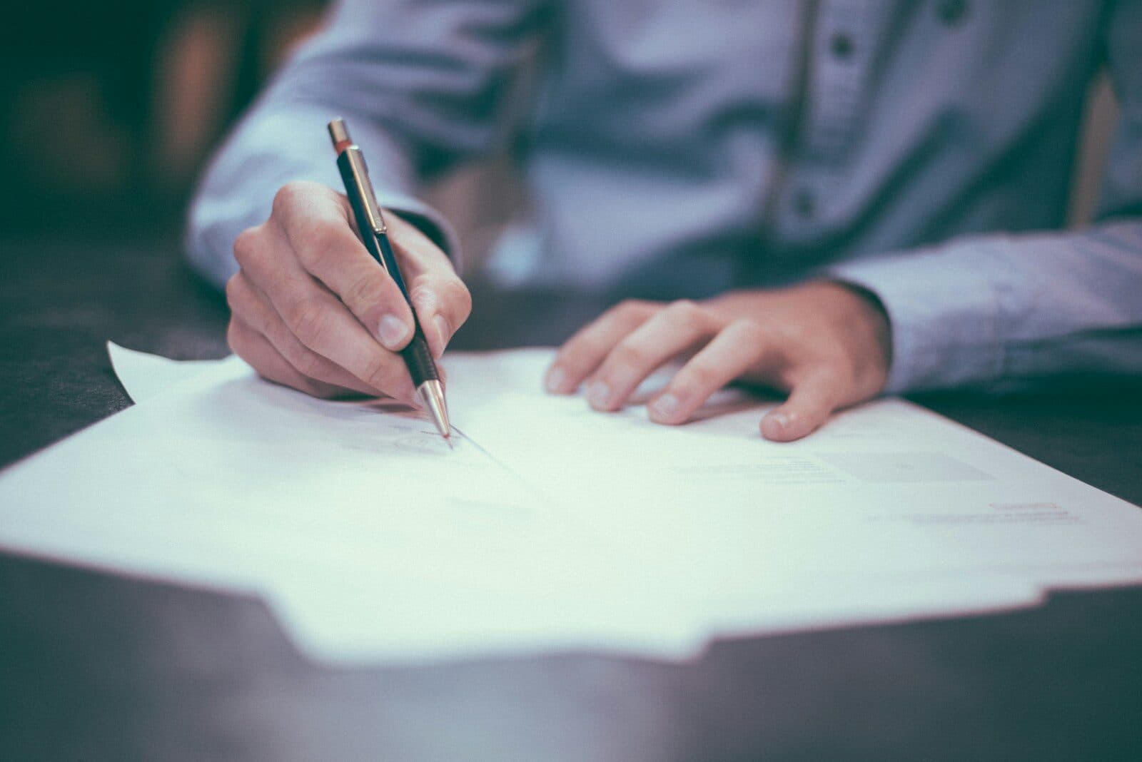 A man signing a paper document at his desk