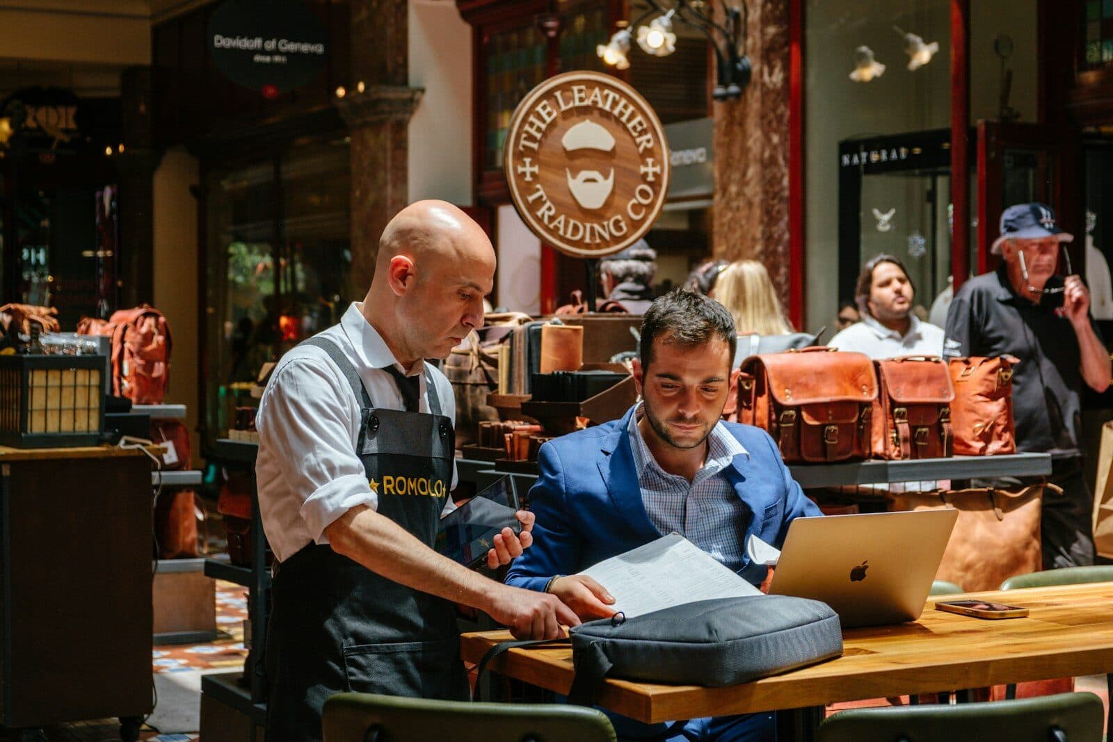 A shop owner and a colleague going over figures on a laptop in their store