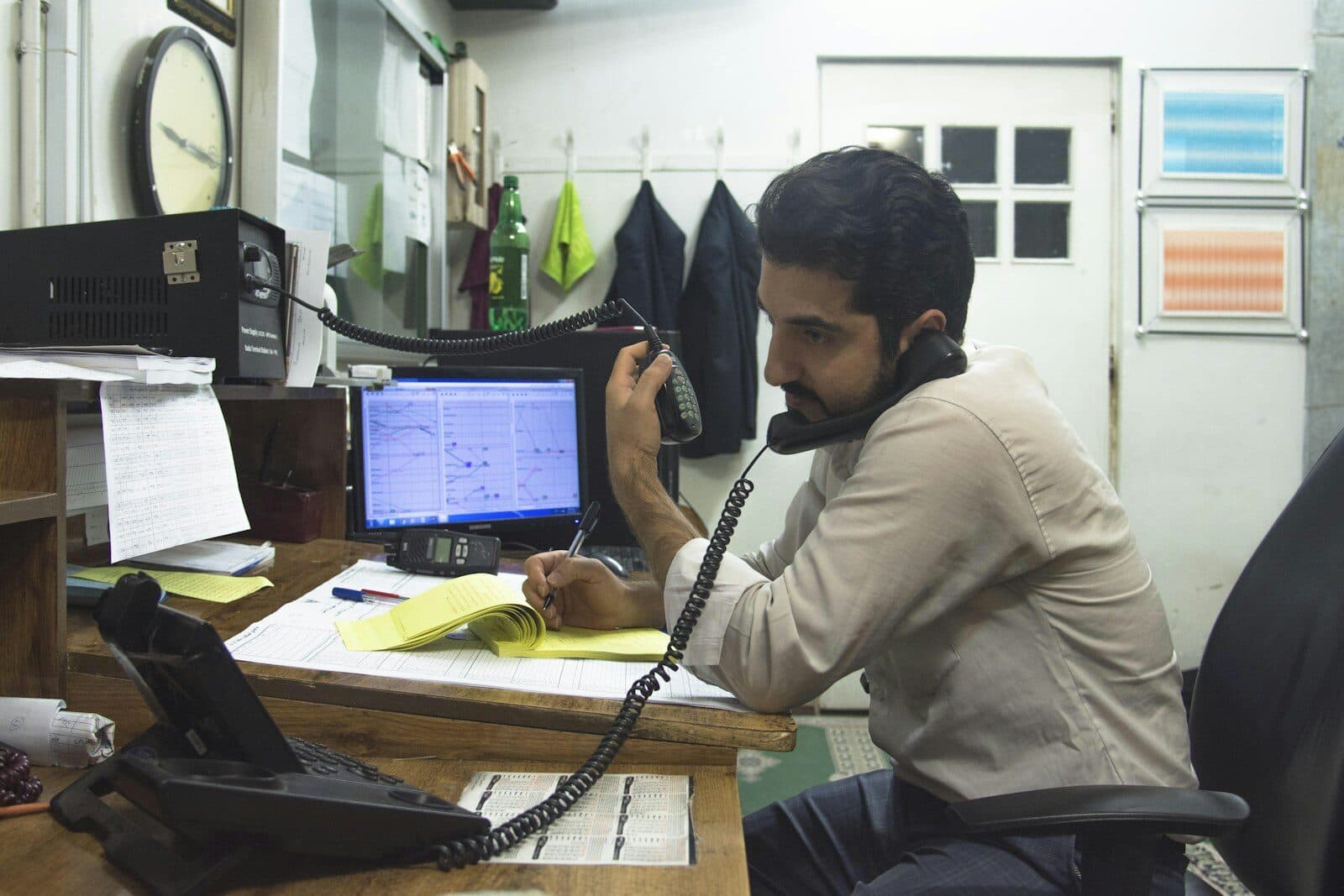 A man on the phone at a cluttered office desk